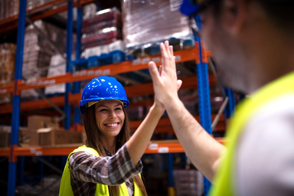 Two warehouse employees reviewing an order list between shelving units